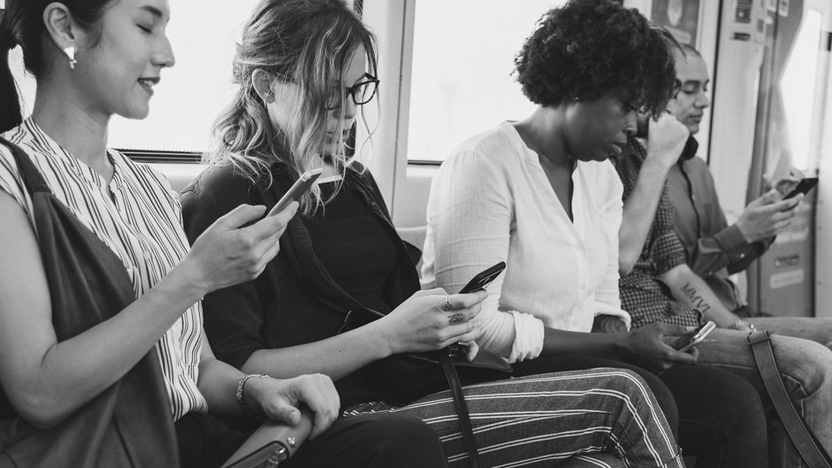 Nhóm người đa chủng tộc ngồi dùng smartphone trên tàu, ảnh đen trắng